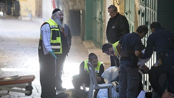 Efectivos de emergencia analizan el lugar donde un joven palestino ha sido abatido.