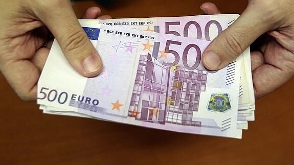 Un empleado de un banco muestra un fajo de billetes de 500 euros.