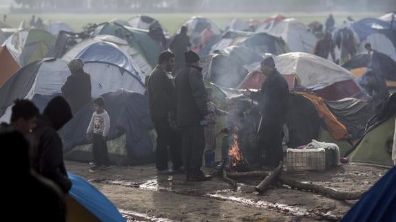 Refugiados entran en calor junto a una hoguera en el campamento griego de Idomeni. 