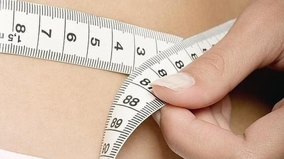 Una mujer se mide la cintura. 
