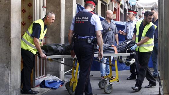 Los agentes judiciales sacan el cuerpo de uno de los fallecidos. 