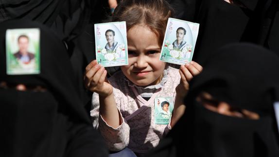 Una niña sostiene dos fotografías en el Día de los mártires en Saná. 