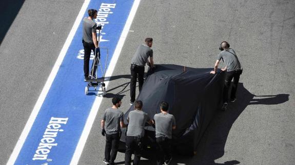 Los mecánicos retiran el monplaza de Fernando Alonso del circuito de Montmeló. 