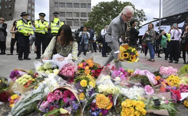 Varias personas rinden homenaje a las víctimas junto al puente de Londres.