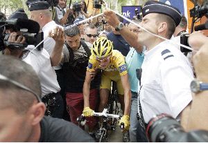 ASEDIO. Michael Rasmussen, protegido por la policía, se dirige hacia la salida de la etapa de ayer en Montpellier. / AFP