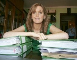 Sara López sonríe apoyada sobre sus apuntes ante la atenta mirada de su padre, al fondo. / L. SEVILLA