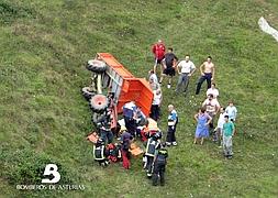 Bomberos asisten al herido junto al vehículo volcado. / BOMBEROS DE ASTURIAS