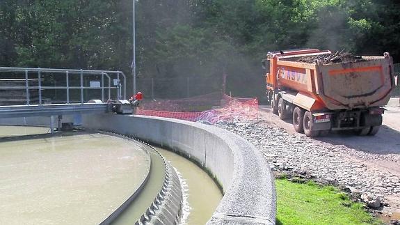 Un camión abandona las obras de la ampliación de la depuradora de San Claudio. En primer plano, el tratamiento de tormentas en funcionamiento.