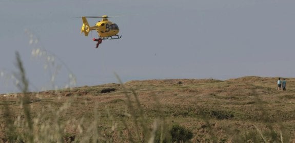 El helicóptero sobrevuela la cima del acantilado portando en una camilla externa el cuerpo sin vida del infortunado joven. 