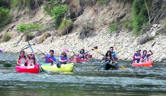 Varios particulares disfrutando del descenso del Sella en canoa durante una jornada estival. 