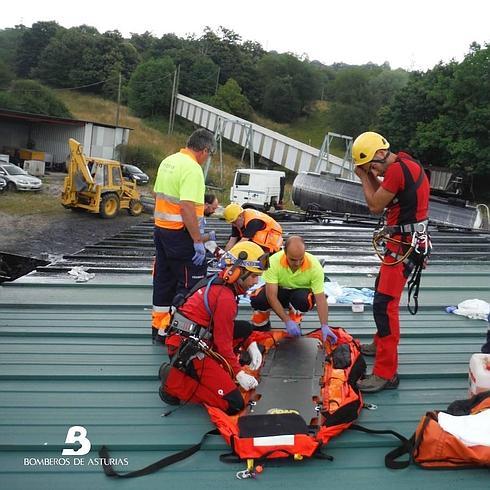 Los bomberos atienden al herido sobre el tejado. 