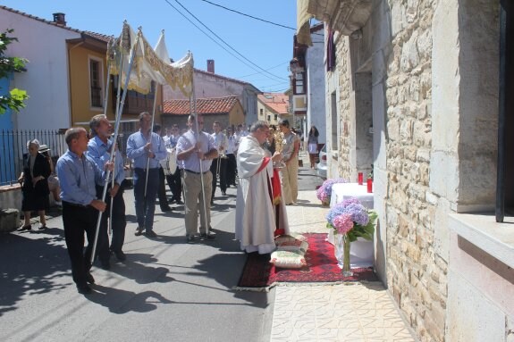 El párroco local sostiene la Custodia durante la parada frente al altar en la fachada de La Casona. 