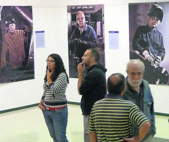Varios visitantes observa unan las fotografías que forman parte de la exposición que acoge el Ateneo de La Calzada. 