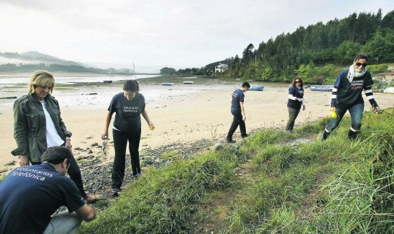 La edil Ana Carmen Fernández y la directora de Telefónica en Asturias, Paula Beirán, en la recogida de residuos en la ría maliaya. 