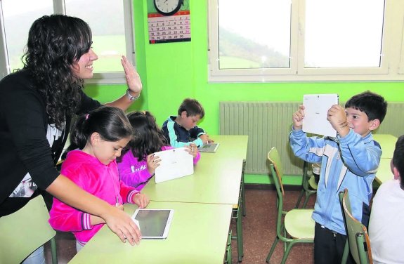 Una profesora ayuda a alumnos de primero y segundo de Primaria a manejar sus tabletas. 