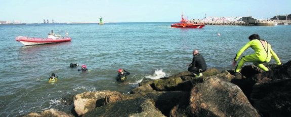 Los buzos del GEAS reciben órdenes desde tierra, con la lancha neumática de la Guardia Civil y la salvamar 'Rigel' detrás de ellos. 