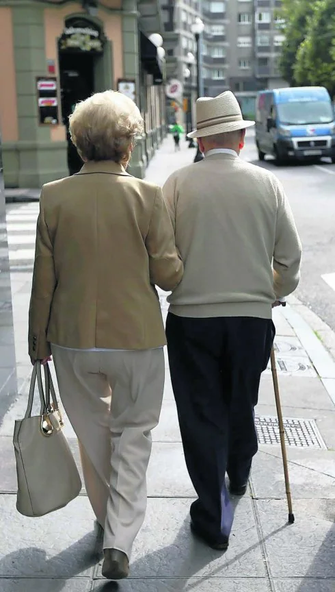 Dos personas mayores caminan por el centro de Gijón. 
