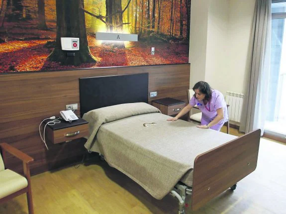 Una empleada del geriátrico del Montepío de la Minería en Felechosa arregla una cama. 