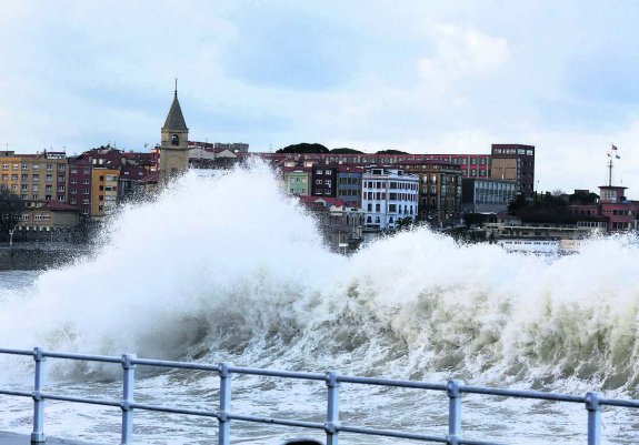 Las olas, golpeando con fuerza el paseo del Muro en Gijón. 