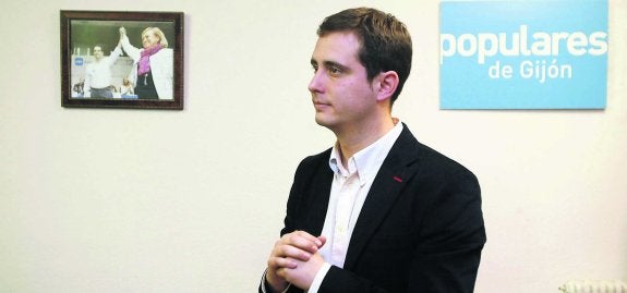 David González Medina, en la sala de prensa del PP, junto a una foto del día de su elección como presidente local del partido. 