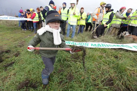 Un niño colabora, pala en mano, en la limpieza simbólica de las marismas junto a más de medio centenar de personas ayer en Maqua. 