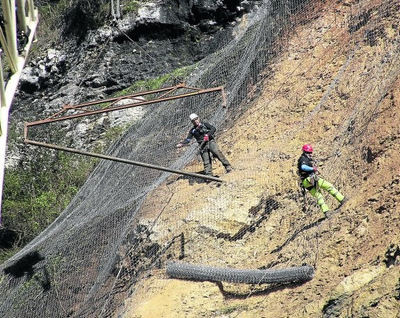 Dos operarios colocando los rollos de la malla de triple torsión ayer en la ladera de Parres. 