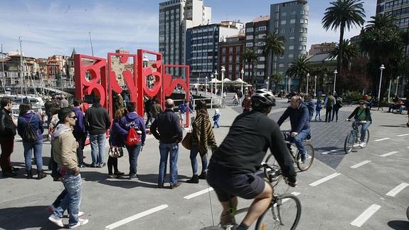 Turistas haciéndose fotos delante de les letrones de Gijón en El Muelle.