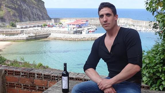 Javier Domínguez, ayer en el puerto de Lastres, al lado de una botella de la bodega D Luis R.