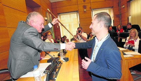 El nuevo alcalde de Siero, el socialista Ángel García, recibe el bastón de mando del concejal de mayor edad, Juan Camino. 