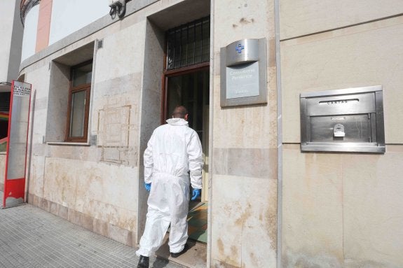 Uno de los operarios, con un traje especial de protección, entra en el consultorio de Lastres, cerrado por Sanidad. 