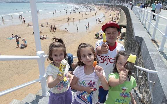Un grupo de niños, ayer, refrescándose con helados en la playa de San Lorenzo de Gijón.Jorge Peteiro
