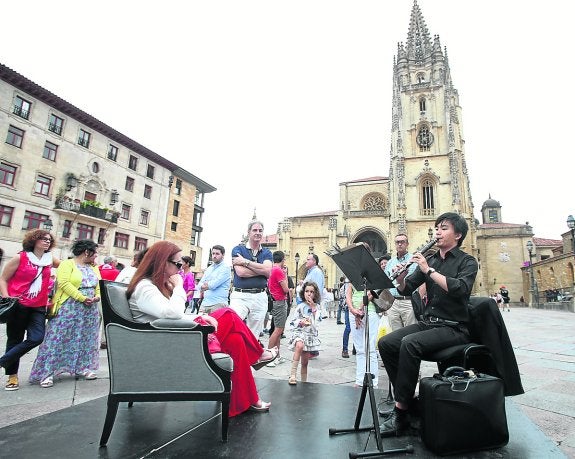 Una mujer escucha, sentada en una butaca, a uno de los alumnos.