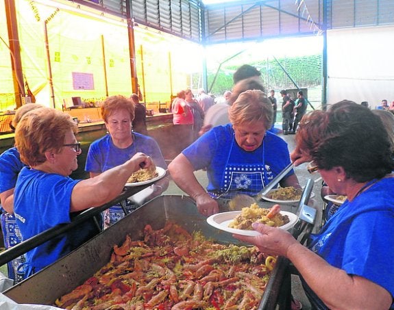 Varias mujeres sirven la paella. 