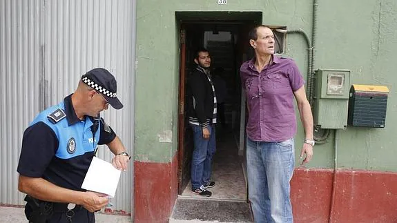 El regidor langreano, ante la vivienda de Barros junto a un policía y un concejal. 
