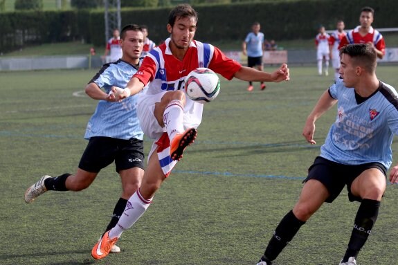 Un jugador del TSK Roces trata de llevarse el balón ante dos rivales. 