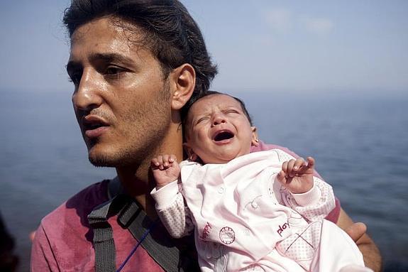 Un refugiado sirio sostiene a su bebé a su llegada a la isla griega de Lesbos.