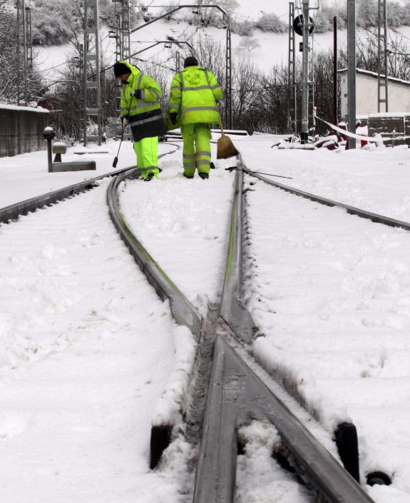Dos operarios tratando de limpiar las vías, durante la nevada que este febrero cortó el tráfico. 