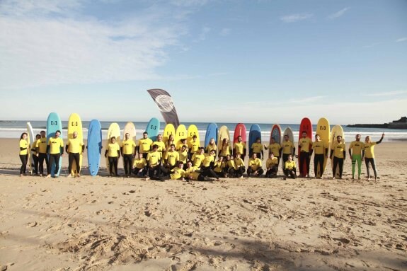 Varias decenas de personas listas para comenzar una jornada de aprendizaje de surf en la playa de Santa Marina. 