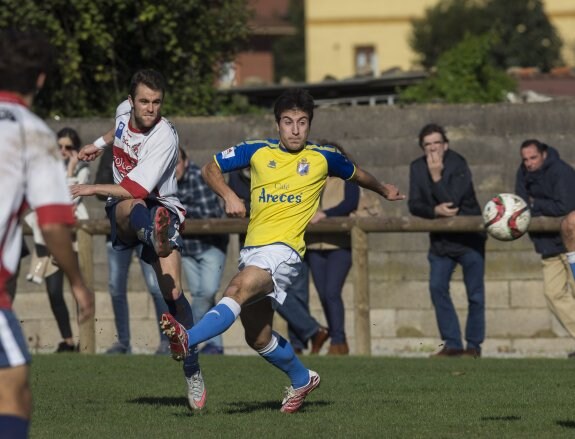 El gijonés Álvaro chuta pese a la oposión de un futbolista del Mosconia. 