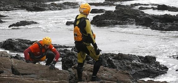 Dos miembros de Bomberos de Asturias rastrean entre las rocas de la playa de Frejulfe en busca del pequeño Hugo Brandomm. 