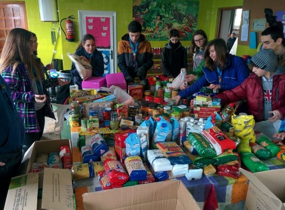 Un grupo de Scouts organiza parte de los alimentos recogidos durante su operación kilo. 