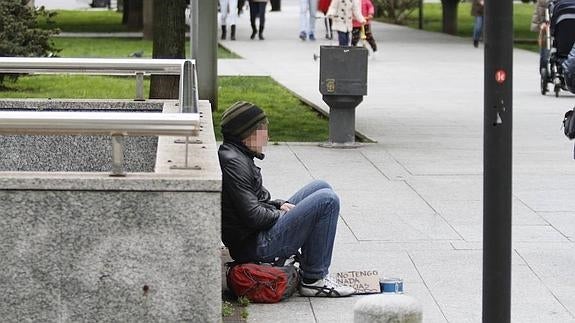 Una persona sin hogar pide limosna en la plaza de Europa de Gijón.