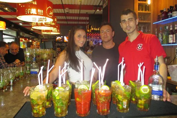 Paco García, propietario del Carlin Goal, entre Jennifer Ochoa y Alin, cocteleros encargados de preparar los trescientos mojitos.