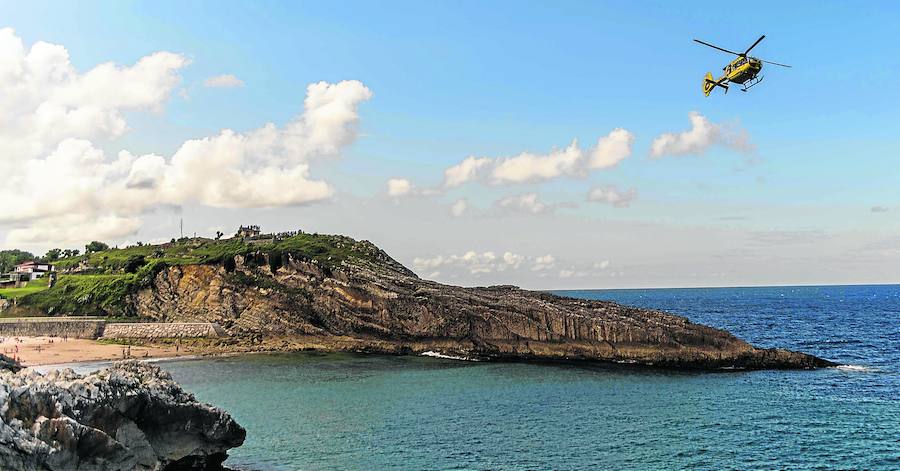 El helicóptero de Servicio de Emergencias del Principado sobrevuela la playa de El Sablón en busca del nadador desaparecido. J