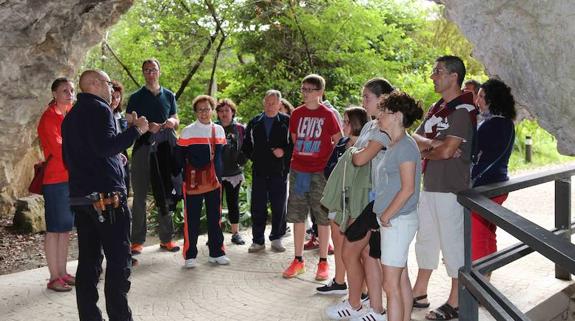 Un grupo de visitantes reciben explicaciones en la entrada de la cueva de Tito Bustillo instantes antes de acceder a la gruta. 