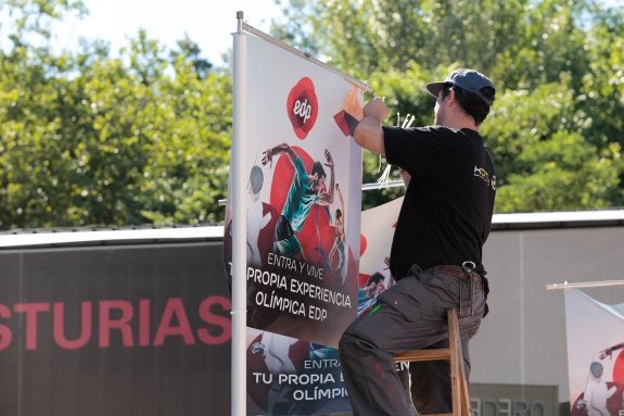 Un trabajador coloca una publicidad de EdP desde una escalera. 