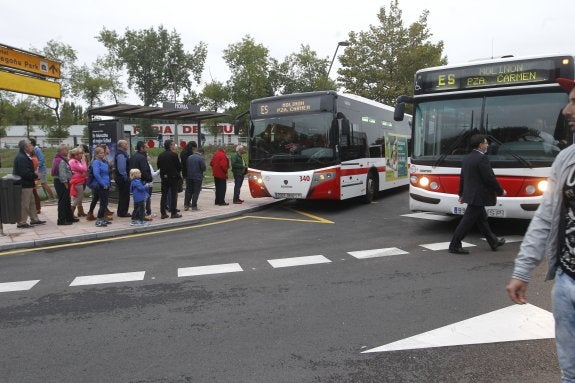 Dos autobuses de la empresa municipal gijonesa, EMTUSA, recogen a pasajeros en una parada. 