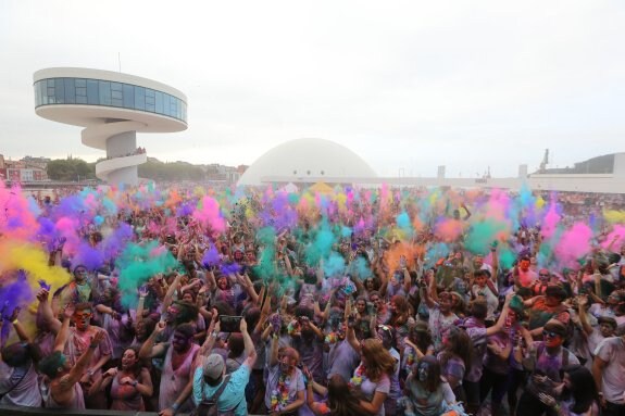 Miles de personas lanzan al aire sus polvos de colores durante una de las actuaciones en la tarde de ayer en la plaza del Centro Niemeyer. 