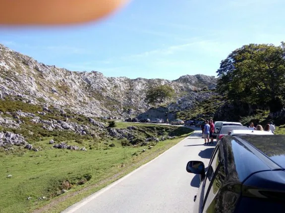 Vehículos atascados en la carretera de acceso a los Lagos de Covadonga con los ocupantes esperando fuera de los turismos. 