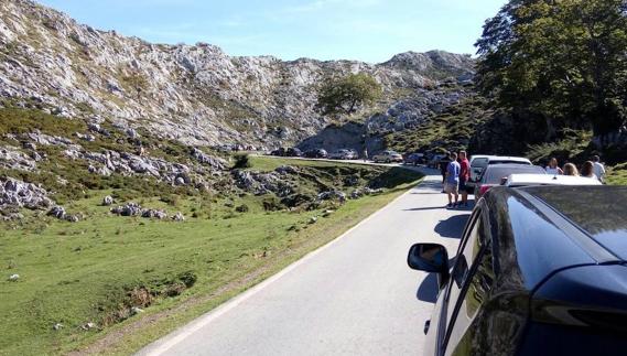 Vehículos atascados en la carretera de acceso a los Lagos de Covadonga con los ocupantes esperando fuera de los turismos. 